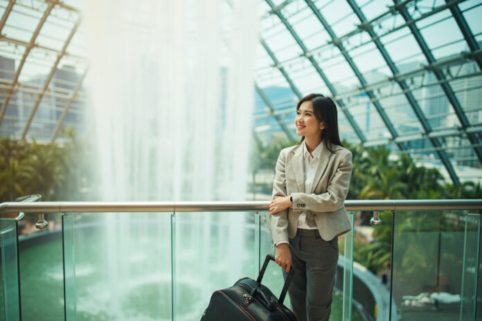 Flight attendant near Jewel Changi Waterfall in Singapore with skyline view